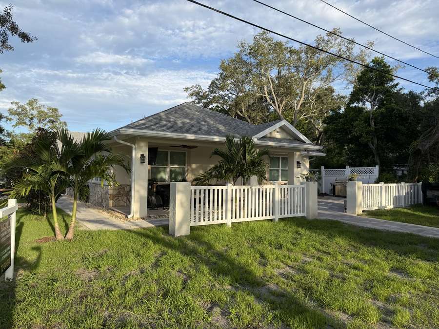Finished custom home in Tarpon Springs with covered porch, palm trees, and white picket fence
