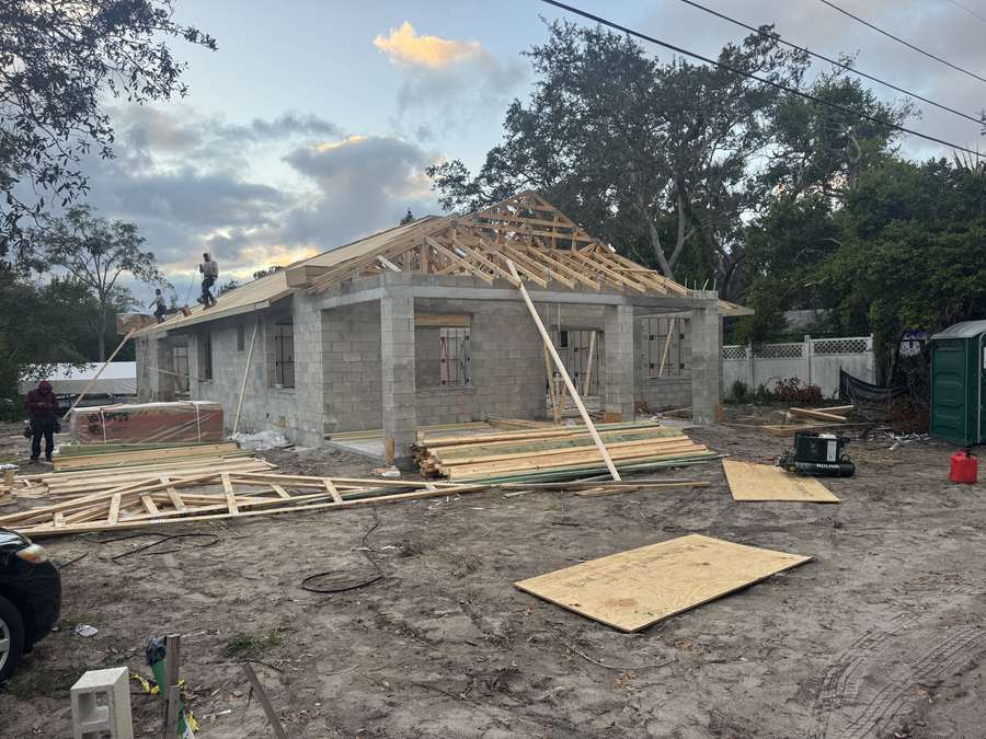 Carpenters setting timber roof trusses on the concrete block walls of a Tarpon Springs home